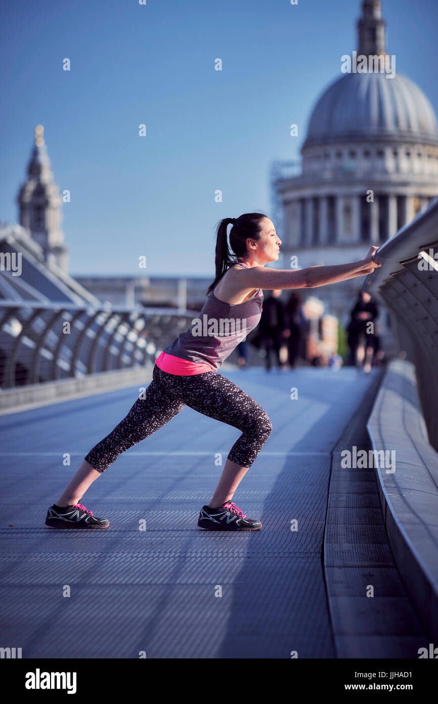Eine Frau ruht auf der Millennium Bridge nach einem Lauf mit St. Pauls Kathedrale im Hintergrund. Stockfoto