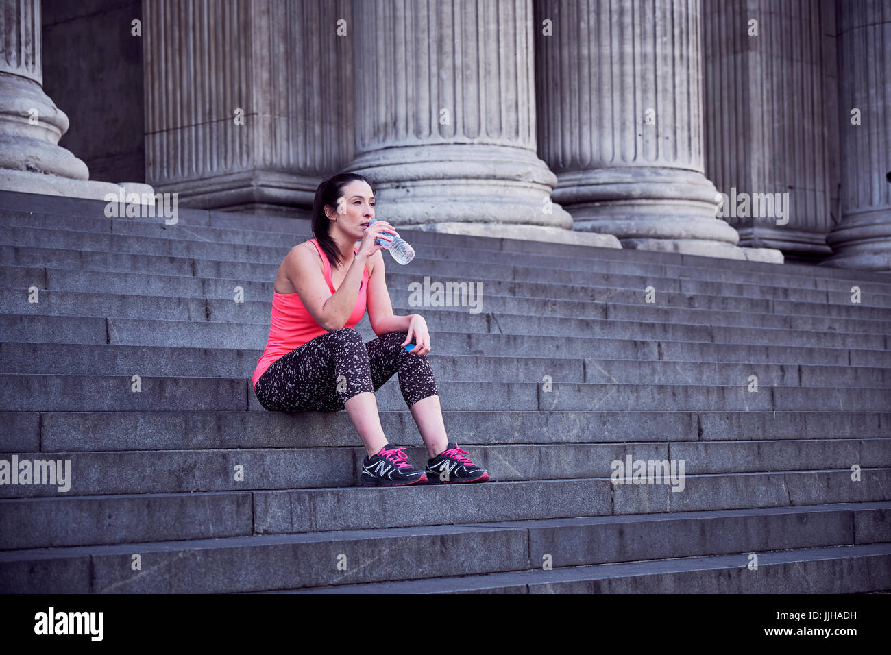 Eine Frau, ruhen Sie sich nach einem Lauf auf den Stufen der St. Pauls Cathedral in London. Stockfoto
