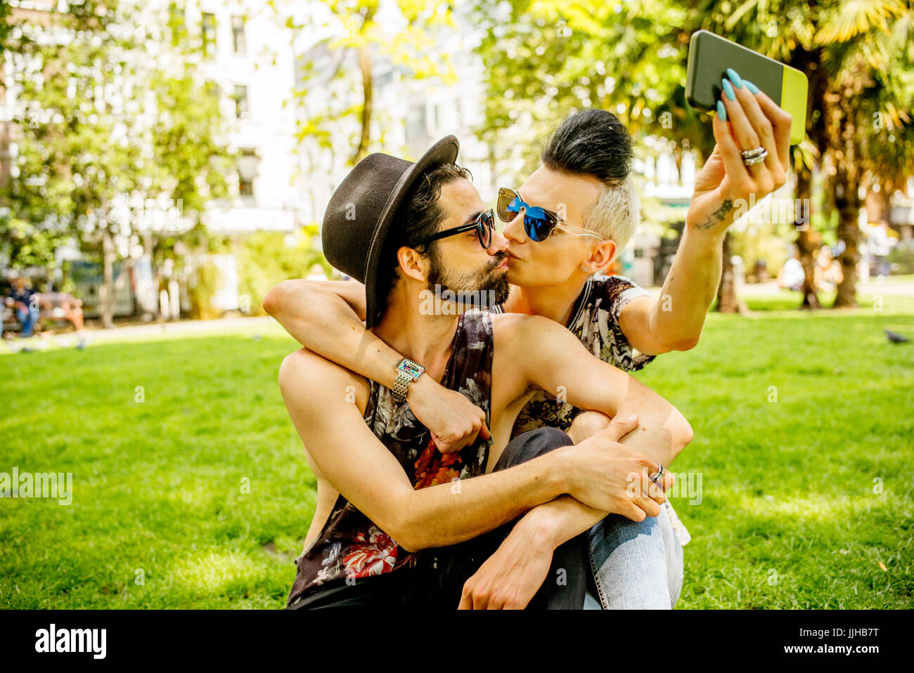 Ein schwules Paar unter Selfies in einem Park in London. Stockfoto