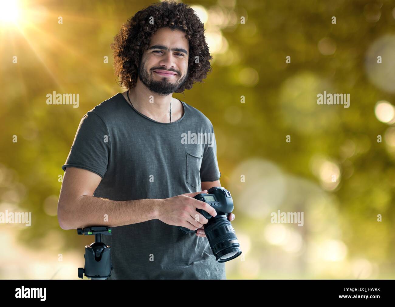 glückliche Fotograf mit Kamera auf Hände und unscharfen Wald mit Lichtern und Fackeln hinter Stockfoto