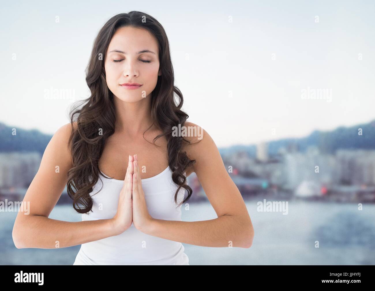 Frau gegen verschwommen Skyline meditieren Stockfoto
