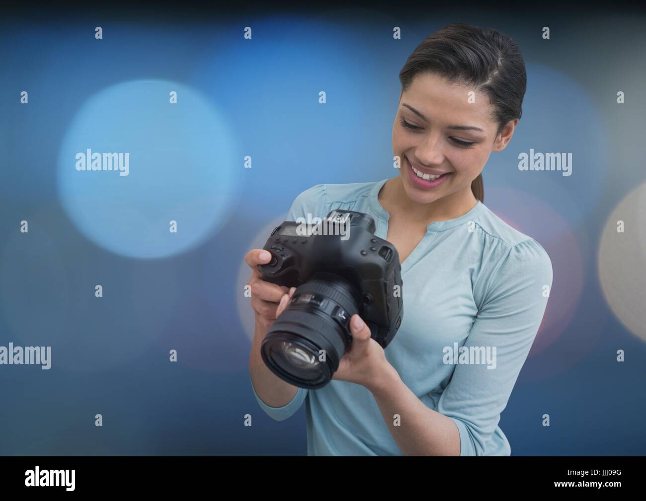 Fotograf, lächelnd, schauen die Fotos auf der Kamera. Verschwommene Blaulicht auf Rückseite Stockfoto
