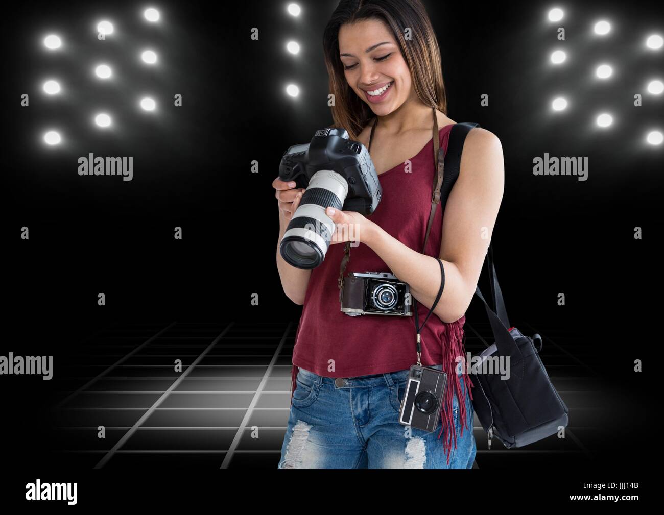 glückliche junge Fotografin sah die Fotos auf der Kamera mit Stadion Lichter hinter Stockfoto