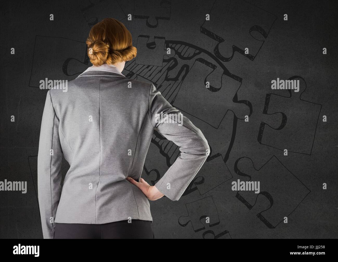 Rückseite des Business-Frau gegen graue Wand und Puzzle-doodle Stockfoto