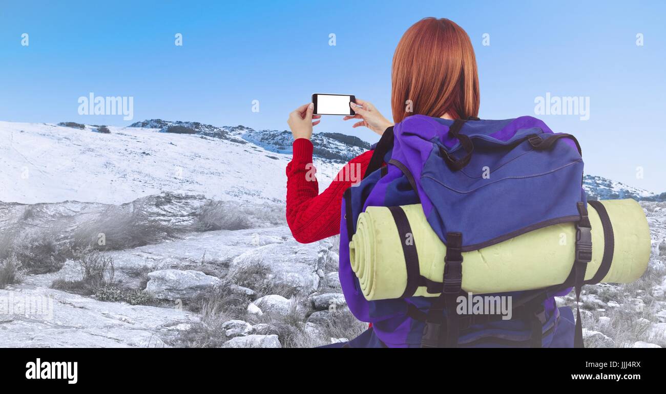 Rückseite des tausendjährigen Backpacker nehmen Selfie gegen verschneite Hügel Stockfoto