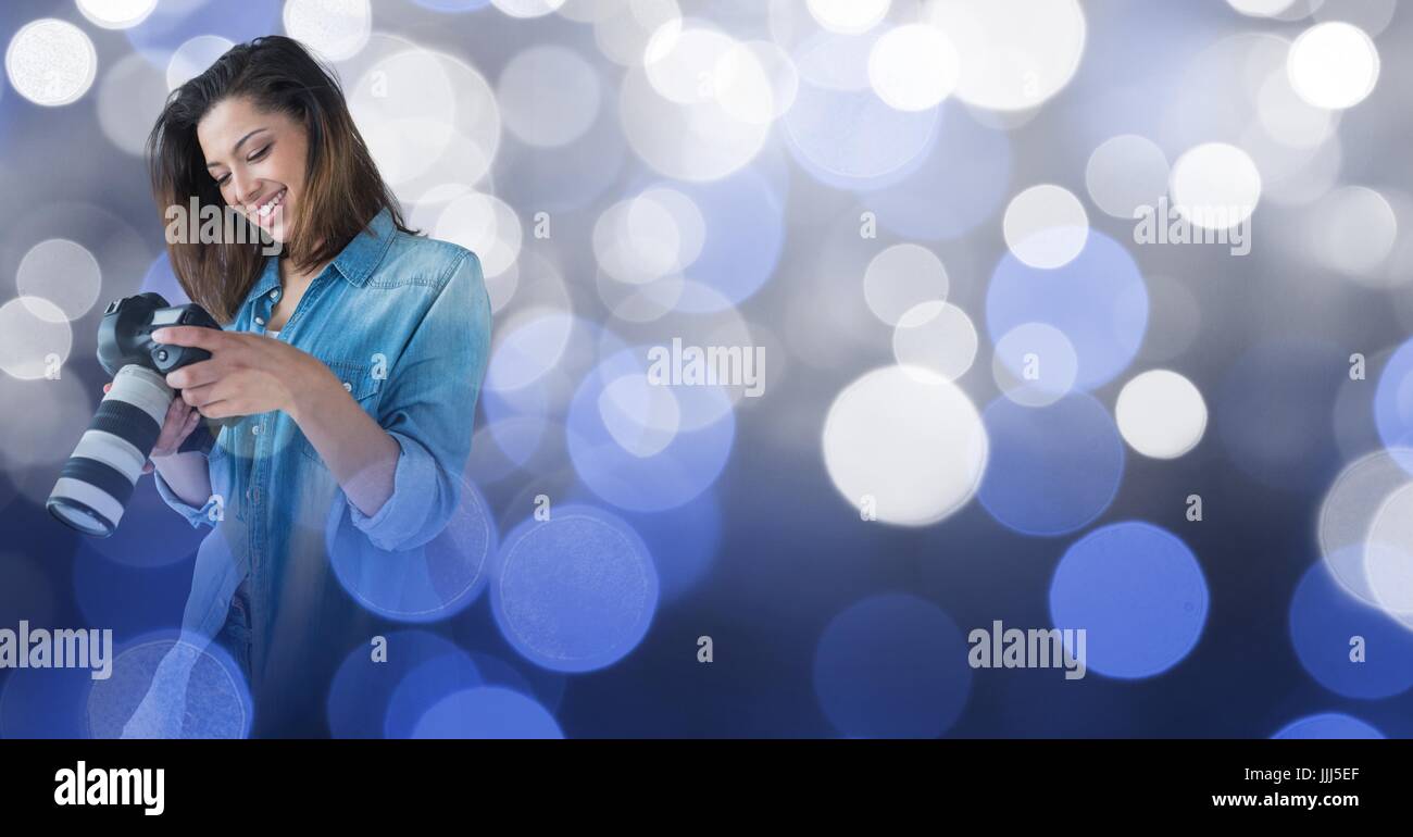 Fotografen, die ihre Kamera vor leuchtenden Hintergrund betrachten Stockfoto