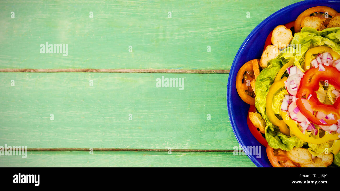 Frische Salate in blau Schüssel am grünen Tisch aus Holz Stockfoto