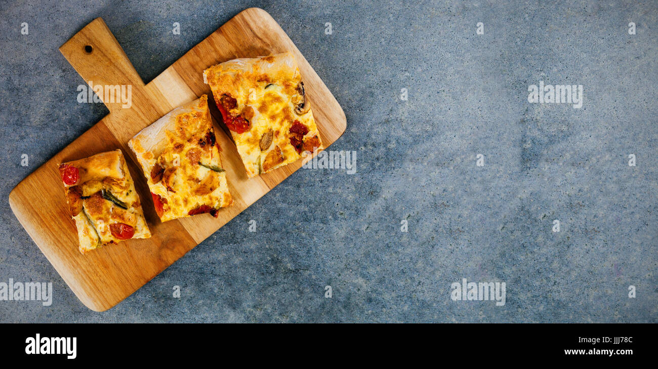 Pizzastücke auf Tablett aus Holz Stockfoto