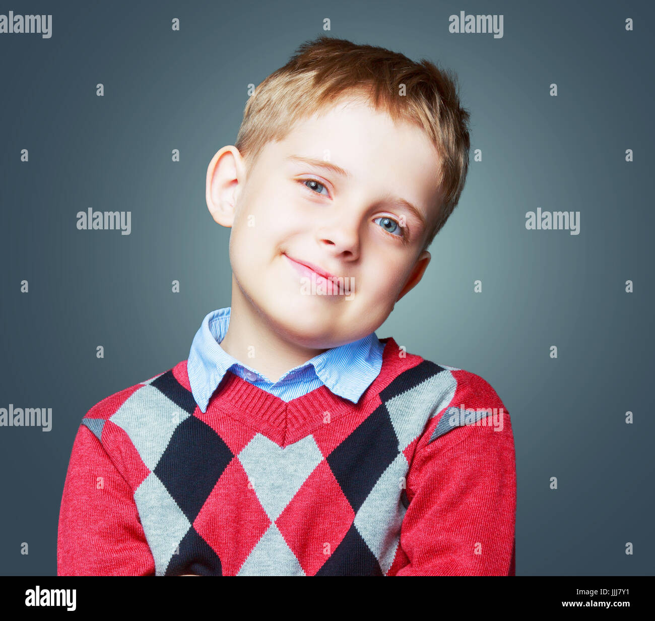 Happy schönes Kind trägt einen Pullover gegen grauen Hintergrund isoliert Stockfoto