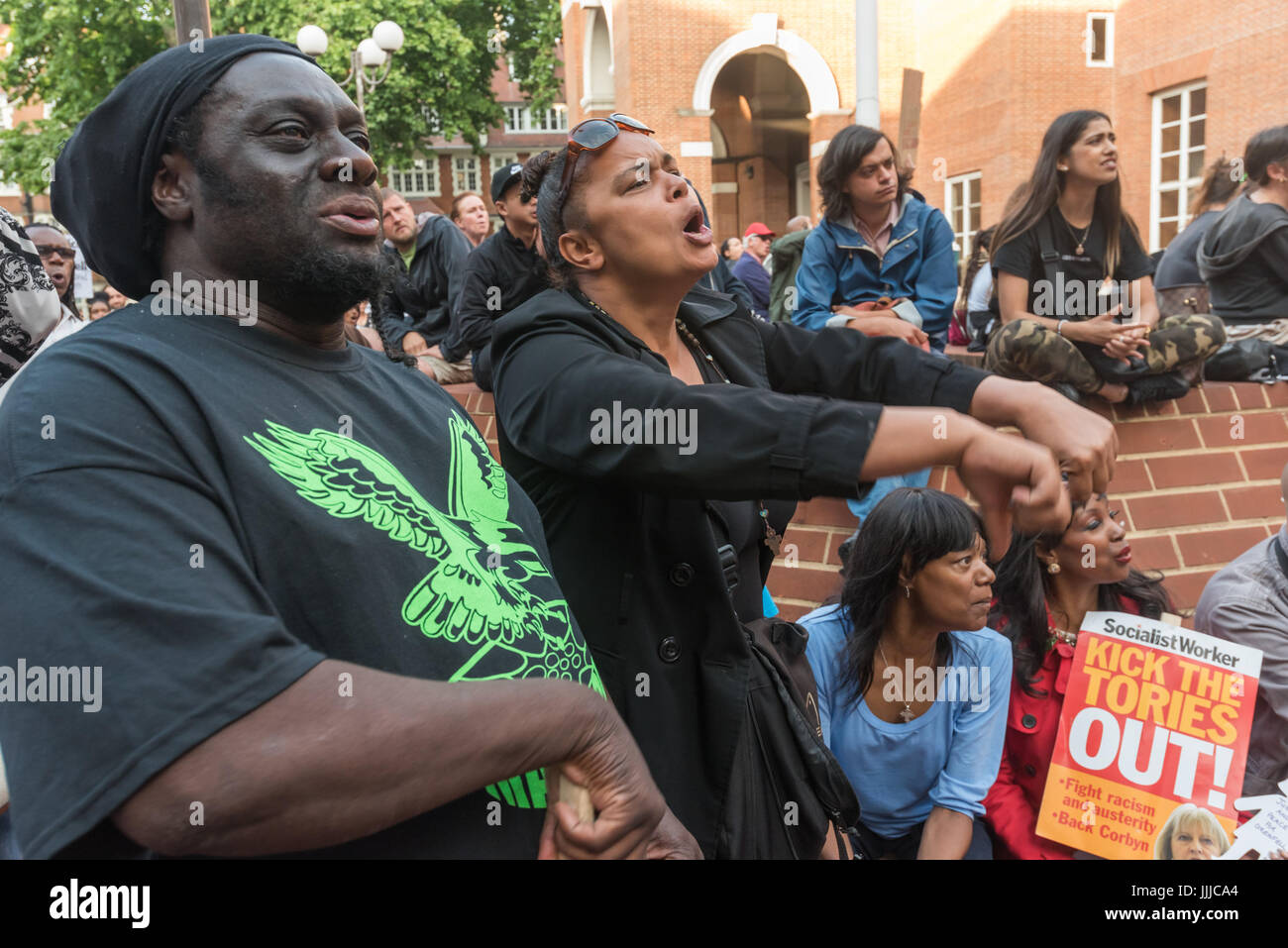 19. Juli 2017 - London, UK - London, UK. 19. Juli 2017. Grenfell Turm Überlebenden und Unterstützer reagieren auf dem riesigen Bildschirm zeigt des Rates in Kensington Town Hall meeting, schreien für Ratsherren "Rücktritt jetzt!" und geben die "Daumen runter". Ein paar hundert Demonstranten besuchte der Rat treffen, obwohl einige Überlebende außerhalb gehalten wurden, bis der Bewohner Vertreter weigerte zu sprechen, bis sie in durften und es viele leere Plätze gab, während Hunderte mehr sahen die Verfahren auf einer Großleinwand außen durchbrechenden mit Wut auf die Selbstgefälligkeit und Bevormundung von einigen Antwerpen Stockfoto