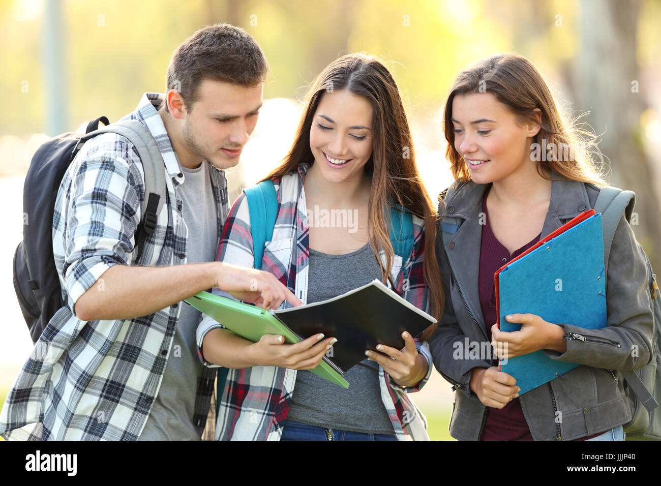 Vorderansicht der drei Studenten lernen ein Notebook lesen und kommentieren auf der Straße Stockfoto