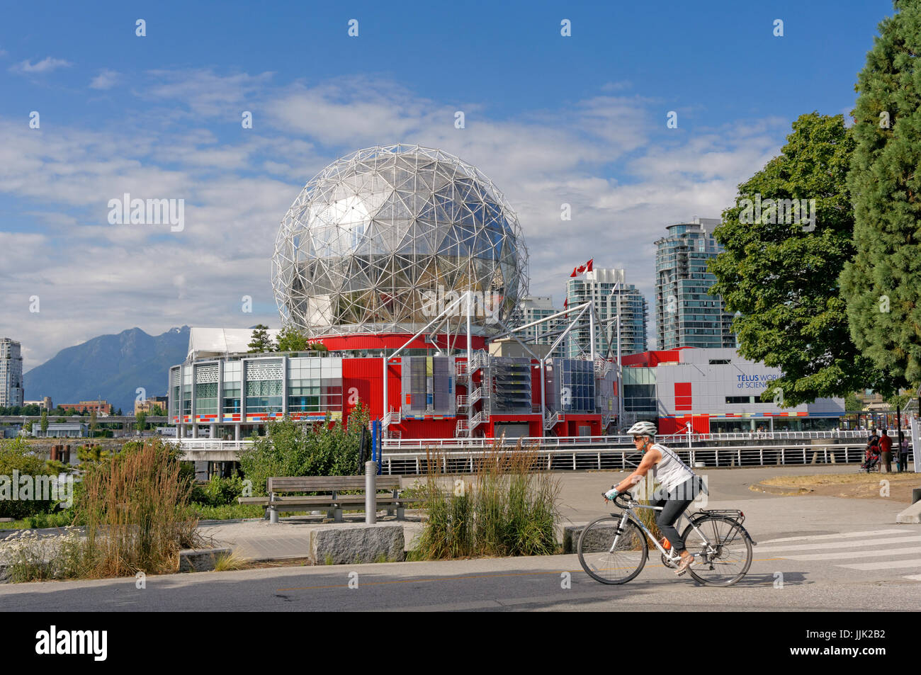 Frau Reiten Fahrrad mit TELUS World of Science Dome auf der Rückseite in das Dorf am False Creek, Vancouver, Britisch-Kolumbien, Kanada Stockfoto