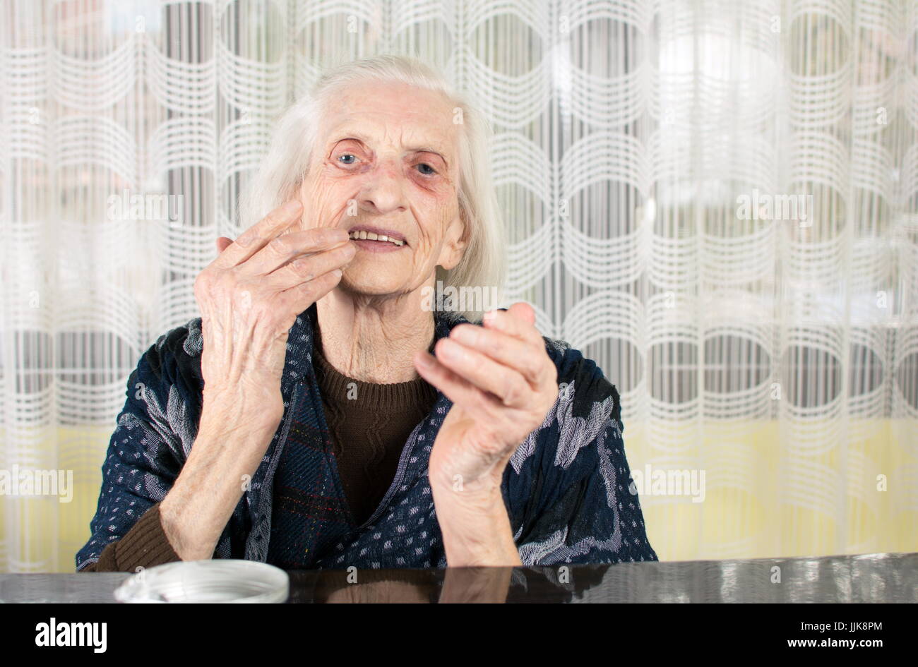 Ältere Frau Gesichtscreme zu Hause anwenden Stockfoto