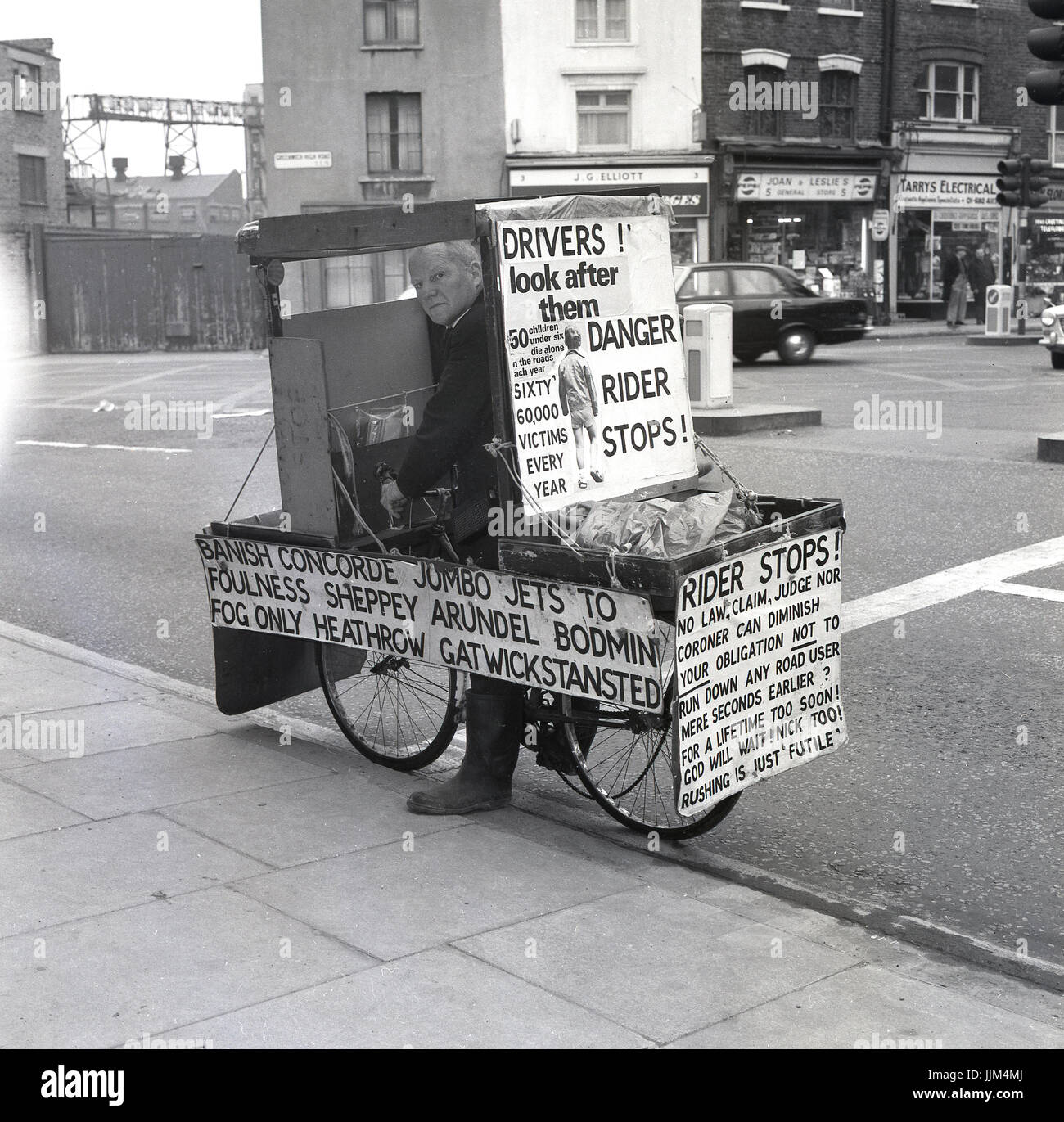 1971, Greenwich High Road, London, Bild zeigt die exzentrische Engländer und glühender politische Kandidaten Lt. Com William (Bill) Boaks auf seine "Kampagnenbus", ein Fahrrad mit Plakaten und Schildern über Sicherheit im Straßenverkehr, eine zentrale Ursache für seine Überzeugungen bedeckt... Stockfoto
