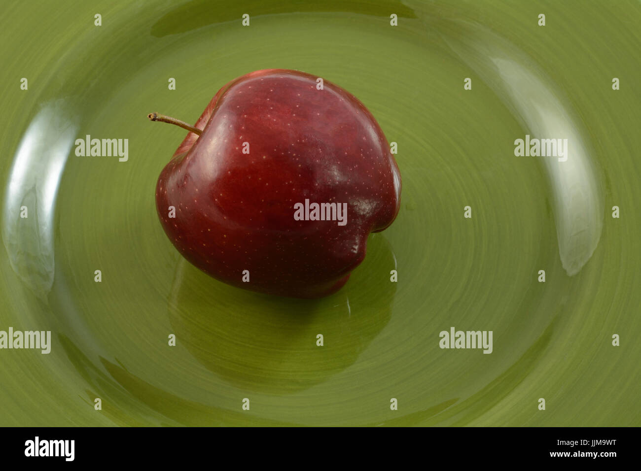 Ende der ganze rohe Red Delicious Apfel auf Teller grün Stockfoto