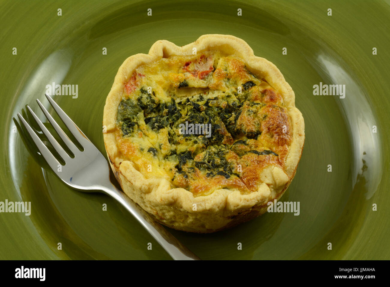 Individuellen Anteil Quiche Florentiner mit Spinat, Feta-Käse und Tomate in grüne Platte Stockfoto