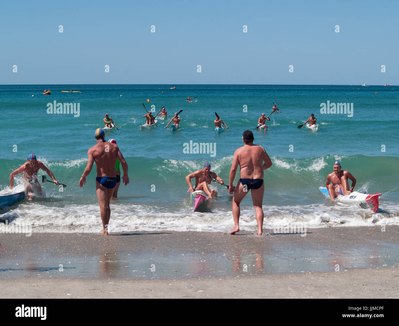 Männer in Kanu paddeln durch Surfen in Wettbewerbe am Mount Maunganui, Surf Lifesaving Rennen 2012 beteiligt. Stockfoto
