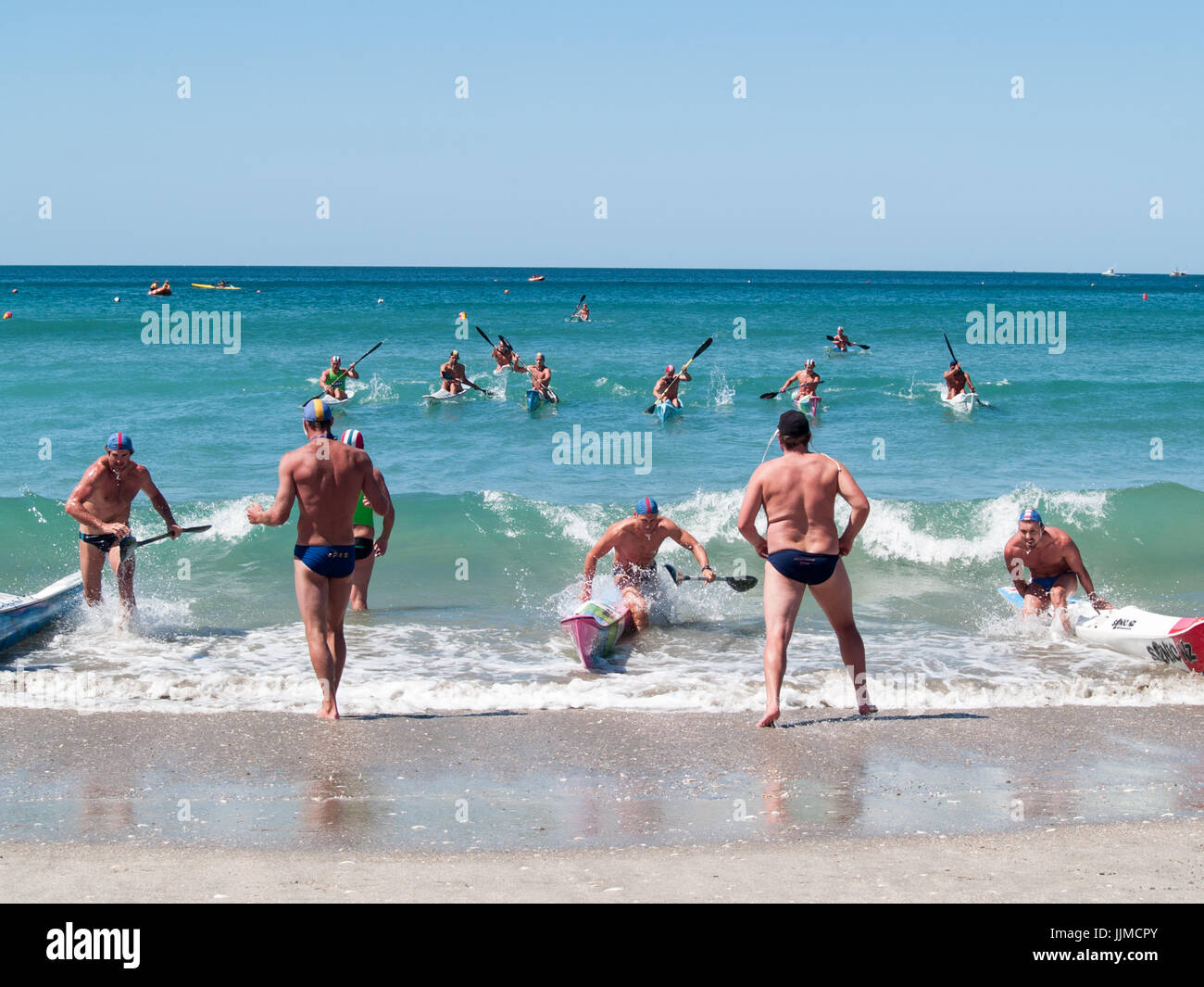 Männer in Kanu paddeln durch Surfen in Wettbewerbe am Mount Maunganui, Surf Lifesaving Rennen 2012 beteiligt. Stockfoto