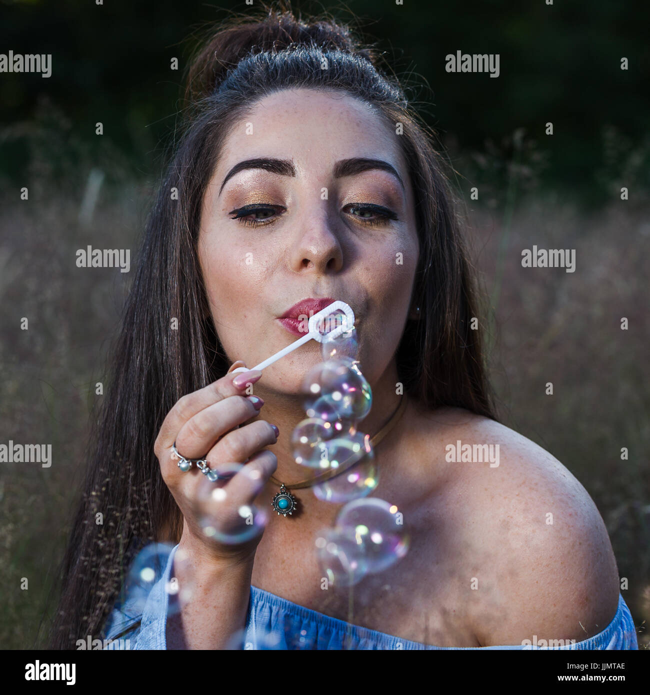 Porträt von meiner Freundin bläst Luftblasen in Richtung der Kamera während eines Outdoor-Foto-Shooting in der Nähe von Liverpool in eine Rasen-Wiese hautnah. Stockfoto