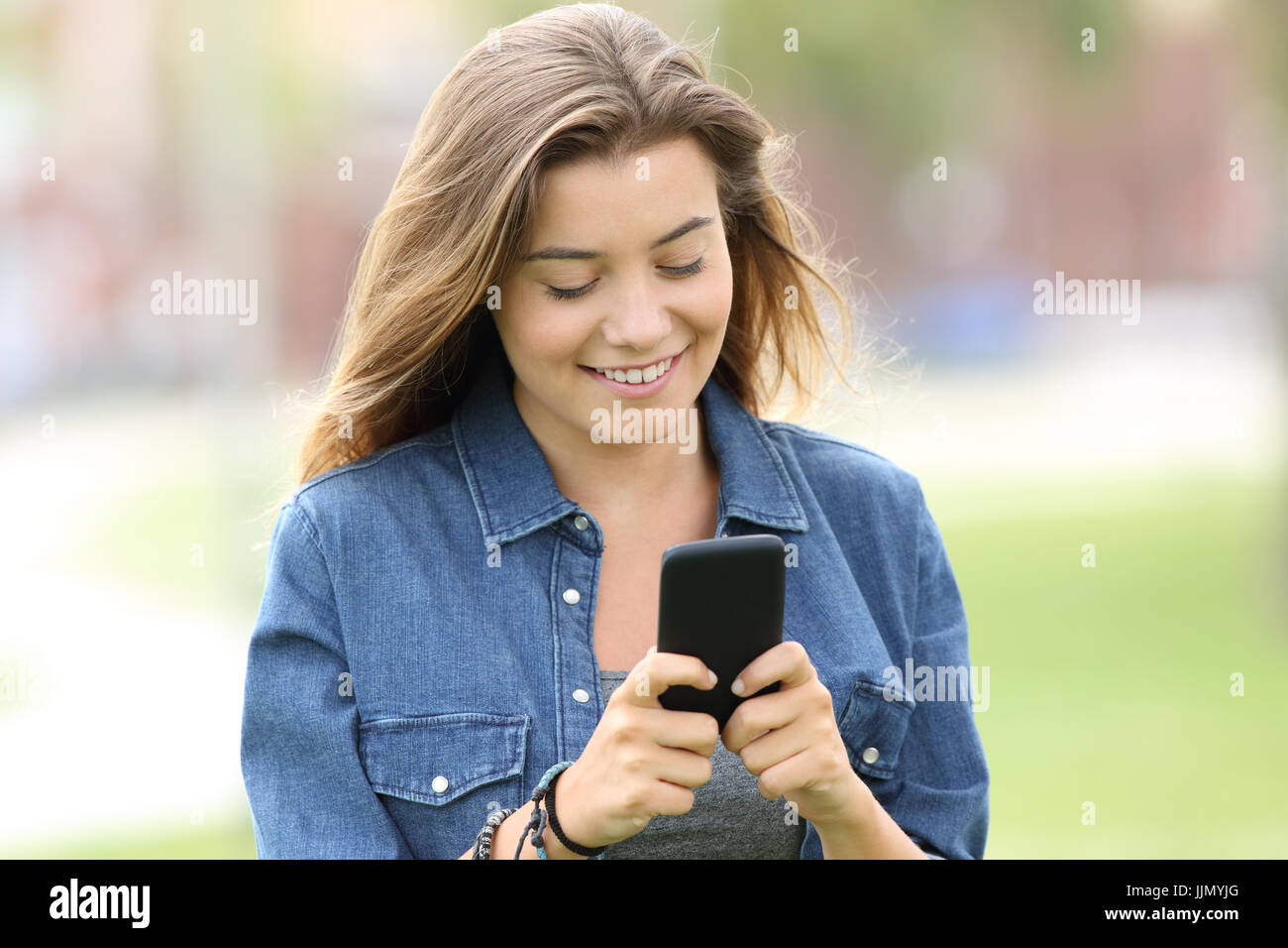 Porträt eines glücklichen Teen Wandern und Lesen von Text in ein Smartphone in der Straße Stockfoto