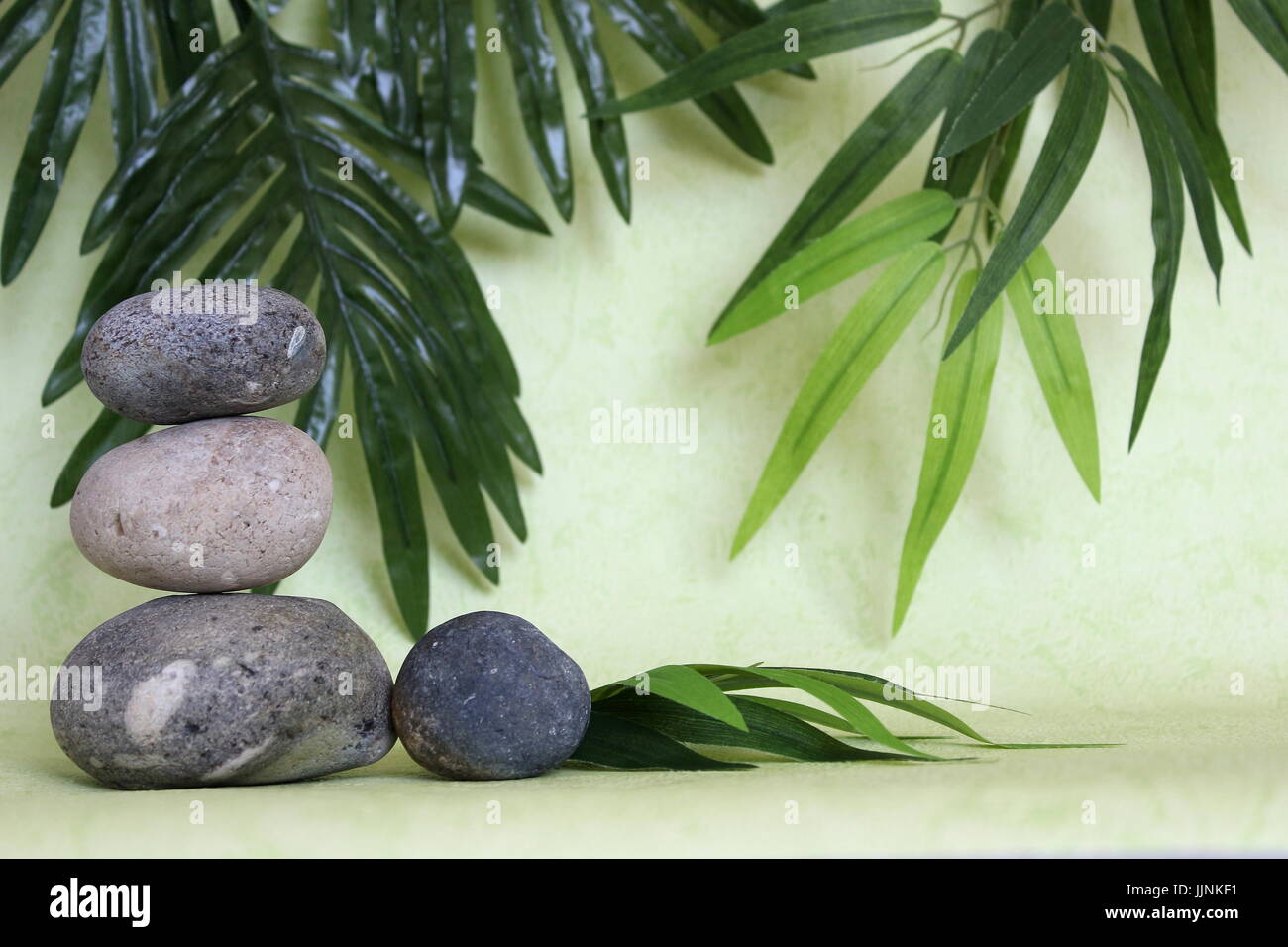Dekorative Kieselsteine in Zen Leben Mode auf grün und Laub Hintergrund gestapelt Stockfoto