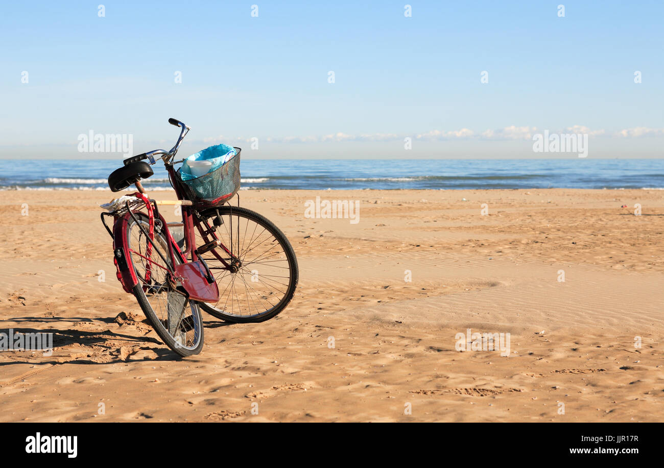 Fahrrad mit Mülleimer stehen am Strand gegen blauen Himmel Stockfoto