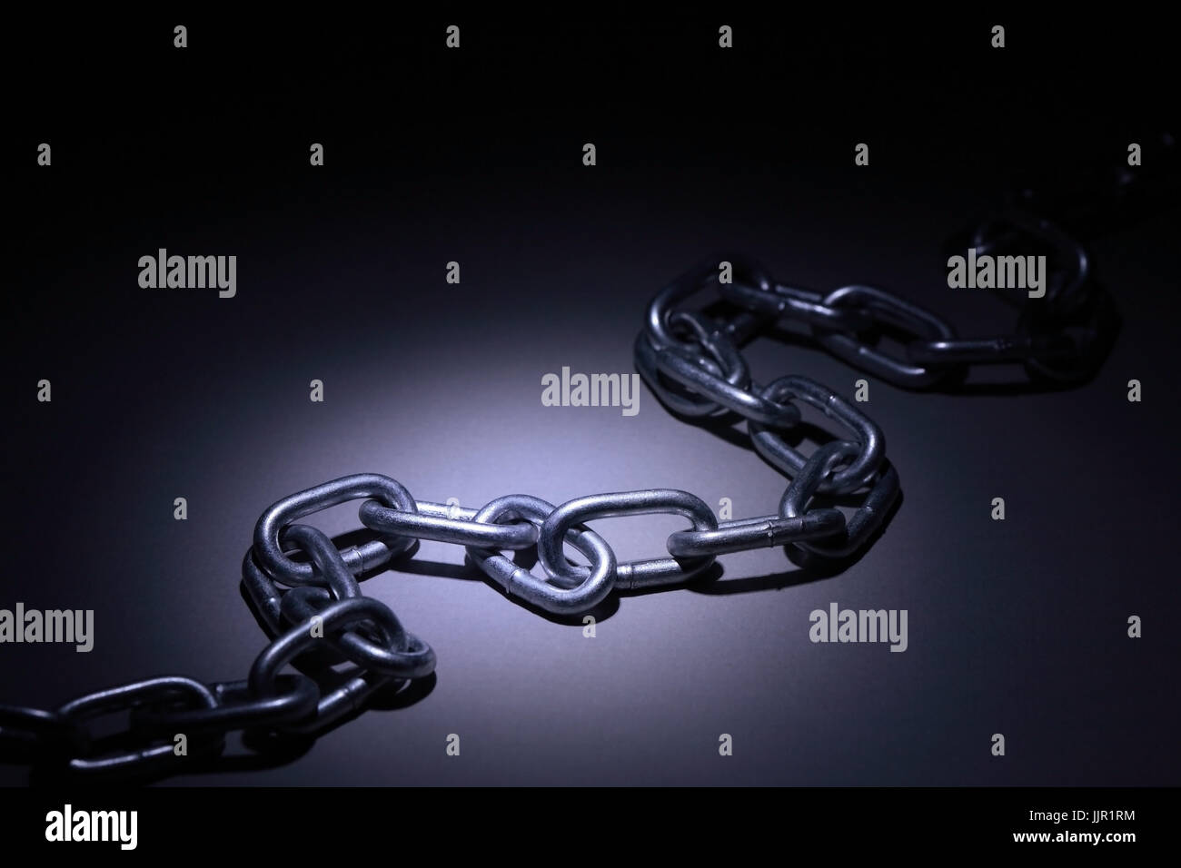 Nahaufnahme von Metall-Kette unter Lichtstrahl auf dunklem Hintergrund Stockfoto