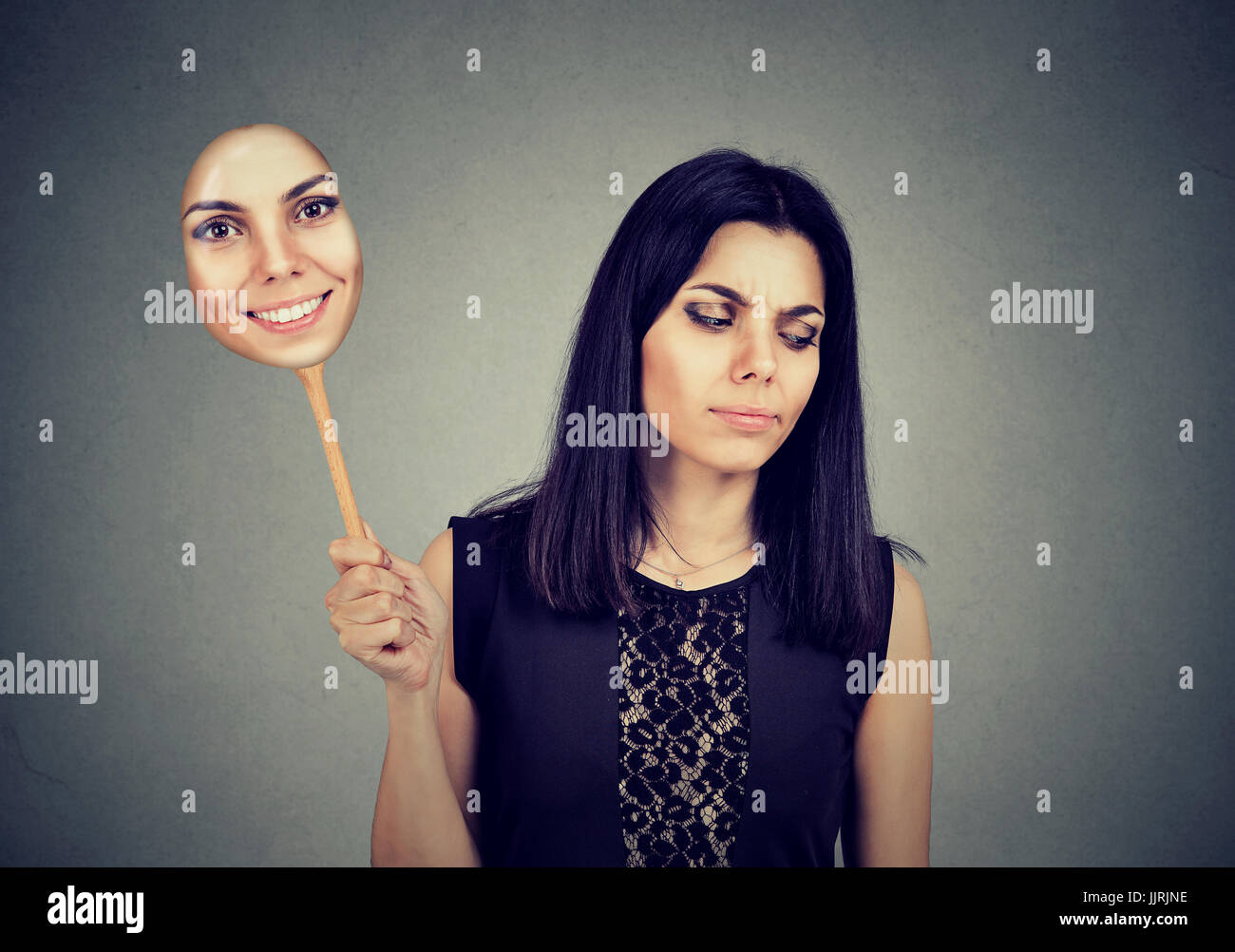 Junge Frau mit traurigen Ausdruck einer Maske mit dem Ausdruck ihrer Fröhlichkeit Stockfoto