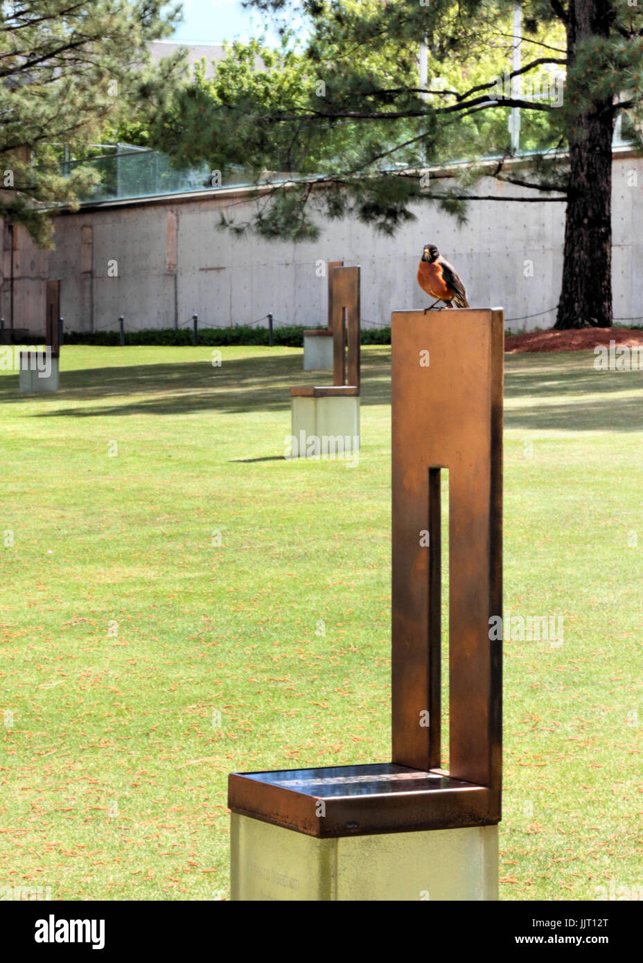 Ein Rotkehlchen sitzt auf einem Denkmal Stuhl an das Oklahoma City National Memorial der Bombardierung des Bundes Gebäudes. Stockfoto
