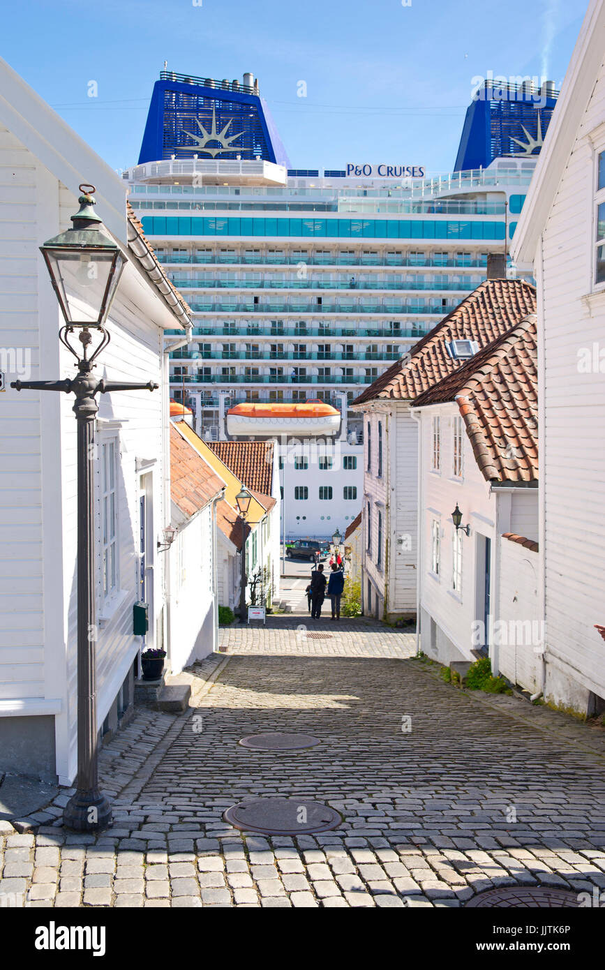 Bahn im Zentrum der Altstadt von Stavanger, Norwegen mit großen Kreuzfahrtschiff im Hintergrund - mv Britannia von P&O Cruises Stockfoto