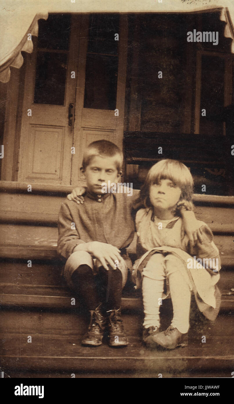 Jungen und Mädchen sitzen auf der Treppe des Hauses. Vintage photo 1915 Russland Stockfoto
