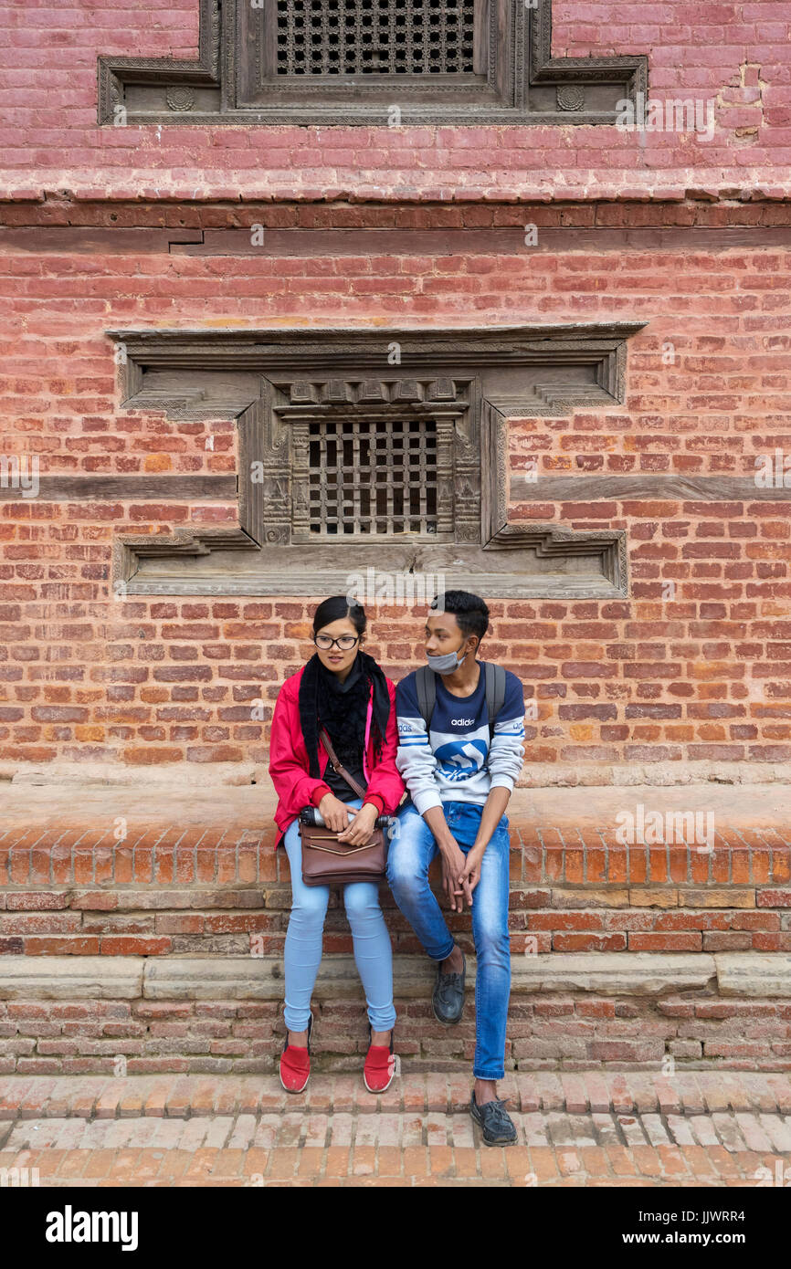 Junge nepalesische Paar in der modernen Kleidung vor einem alten Gebäude in Durbar Square, Kathmandu gekleidet sitzen Stockfoto