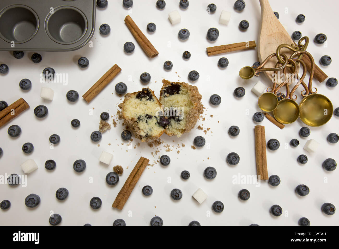 Blaubeere Streusel Muffin mit ganzen frischen Heidelbeeren, Holzlöffel, Messung von Löffel und Muffinformen auf weiß. Stockfoto