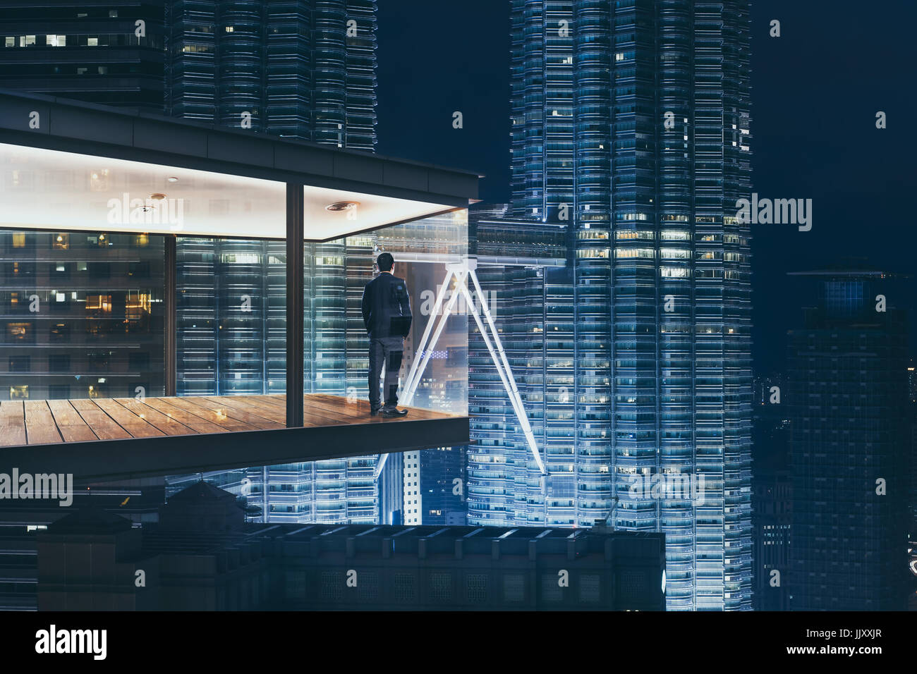 Geschäftsmann in einem modernen Himmel Büro bei Nacht mit Blick auf die schöne Stadt Skyline. Stockfoto