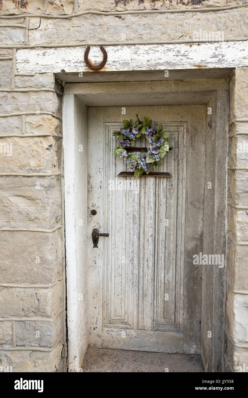 Blumengebinde auf Holztür in Steinmauer von rustikalen Altbau. Stockfoto Blumengebinde auf Holztür in Steinmauer von rustikalen Altbau. Stockfoto