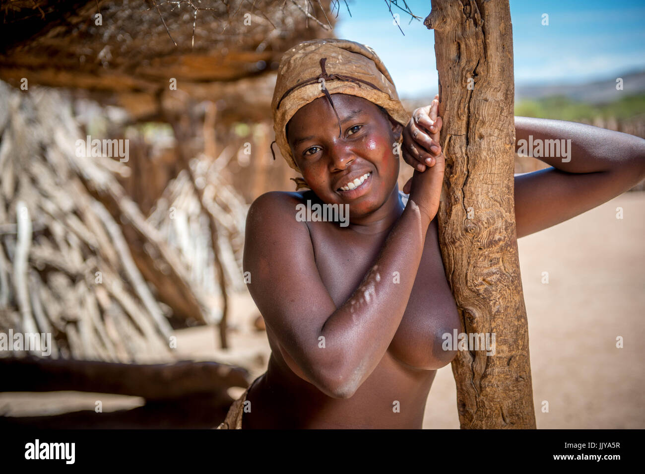 Damaraland Frau steht gegen einen Pfeiler und Lächeln für die Kamera. Die Damara Living Museum liegt nördlich von Twyfelfontein in Namibia, Af Stockfoto