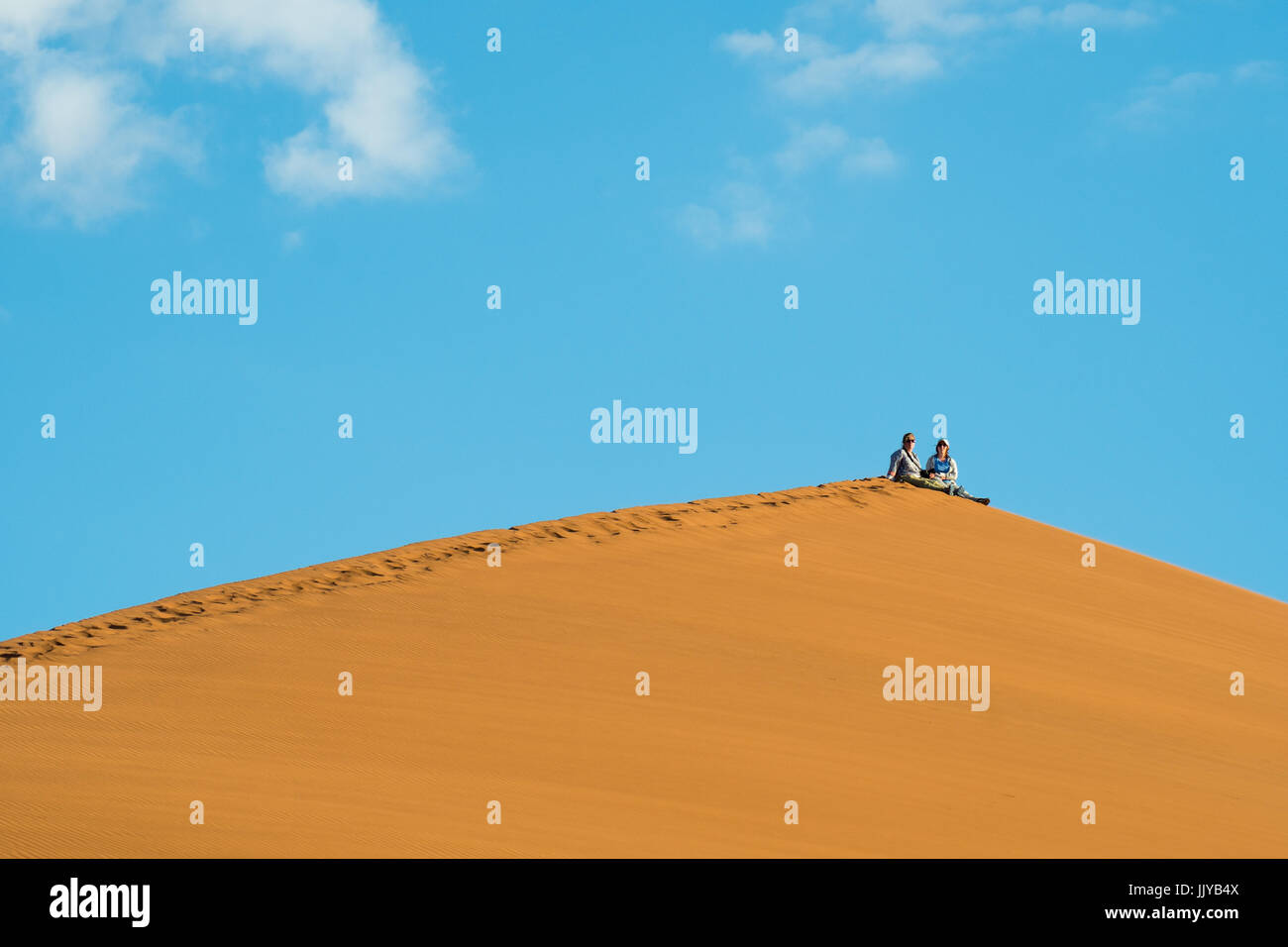 Touristen sitzen oben auf der Düne 45, befindet sich über 170 Meter hoch, in den Soussuvlei Salzpfanne in Namib-Naukluft Nationalpark in Namibia, Afrika. Stockfoto