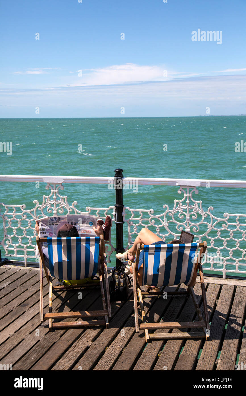 Brighton, UK. 21. Juli 2017. Warmer Tag in Brighton. Paar Sonnenbad auf den Liegestühlen am Pier von Brighton. Bildnachweis: Rob Carter/Alamy Live-Nachrichten Stockfoto