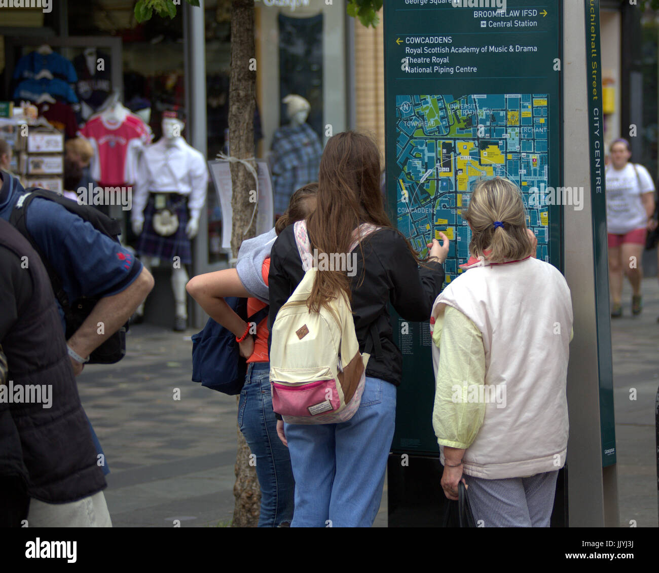 Touristen finden Sie Straßenkarte von Glasgow in der Sauchiehall Street mit Dummys Kilts Tartan Hintergrund Stockfoto