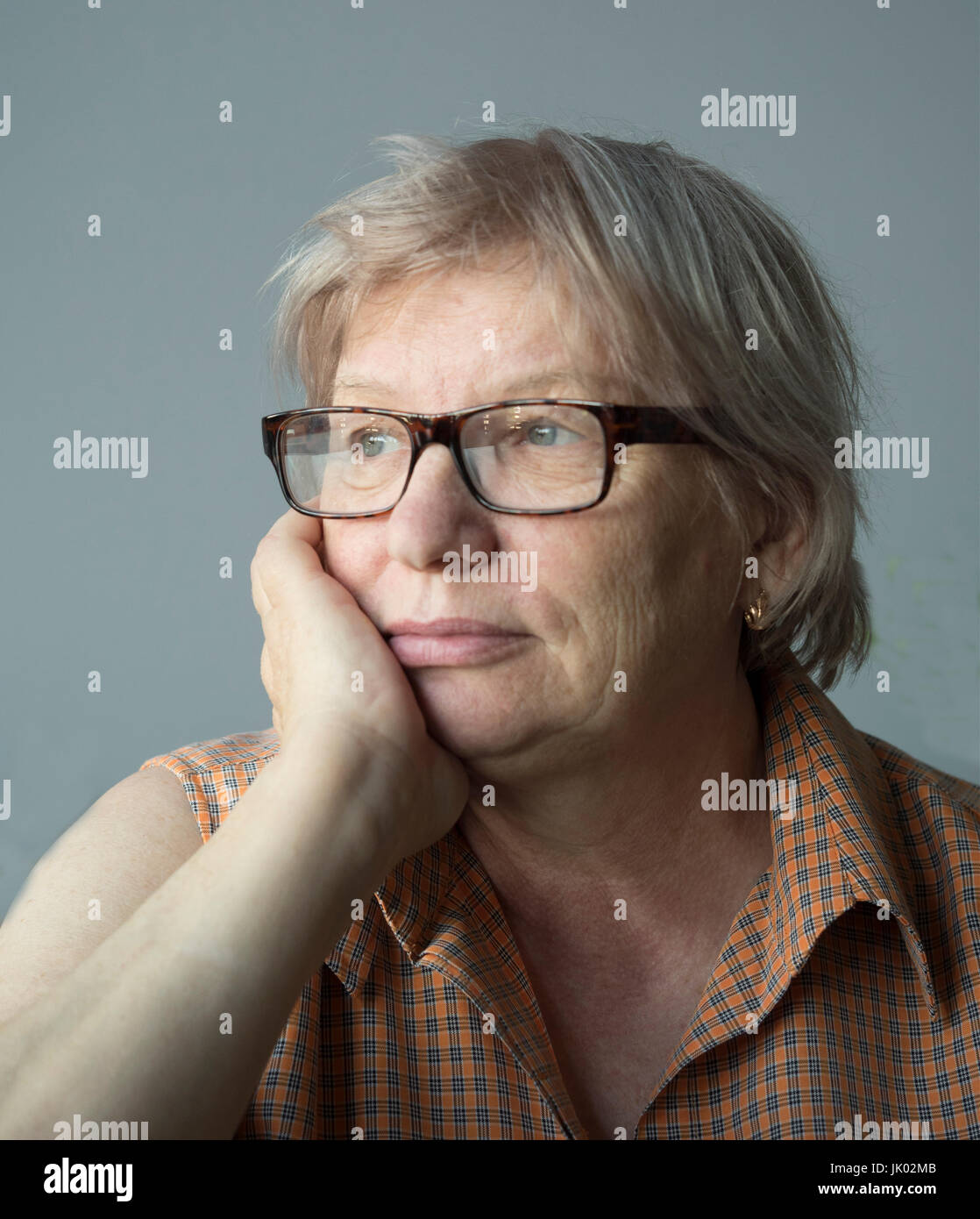 Kaukasischer Frau mittleren Alters sitzt mit dem Kopf in der hand Stockfoto