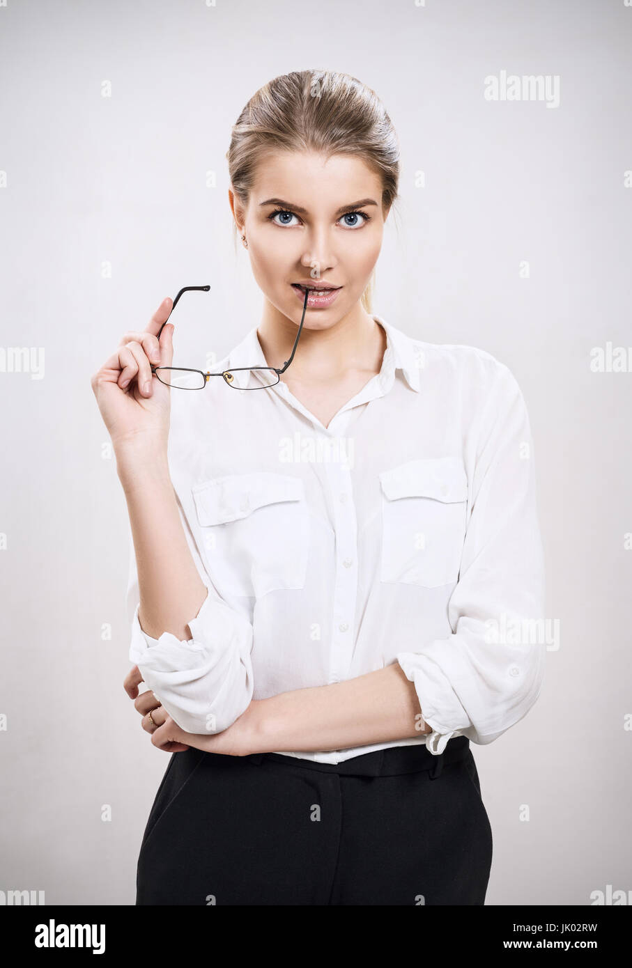 Attraktive Geschäftsfrau, Gläser in Händen hält, auf grauem Hintergrund. Stockfoto