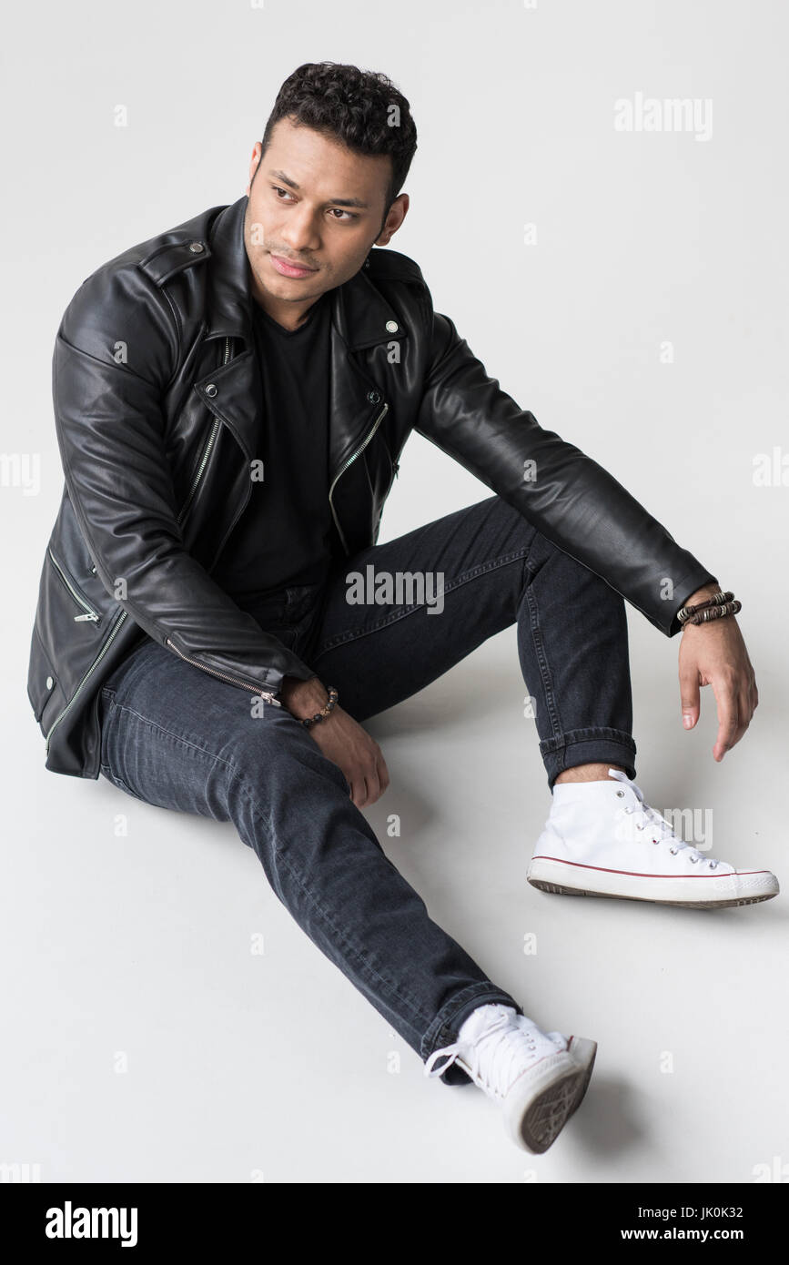 nachdenkliche junge afroamerikanischer Mann sitzt auf grau isoliert Stockfoto