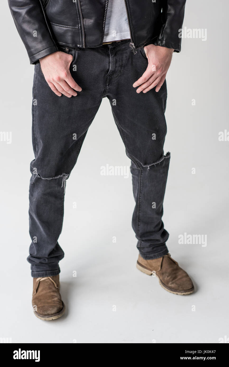 geringen Teil junger Mann posiert in zerrissenen Jeans isoliert auf grau Stockfoto