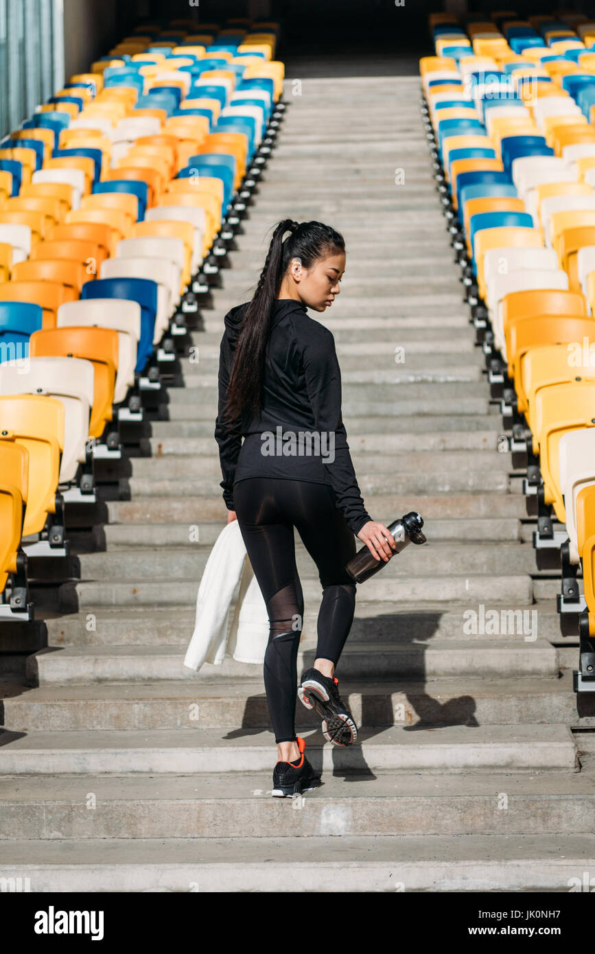 müde asiatischen Sportlerin mit Sport-Flasche und Handtuch auf Stadionsitze Stockfoto