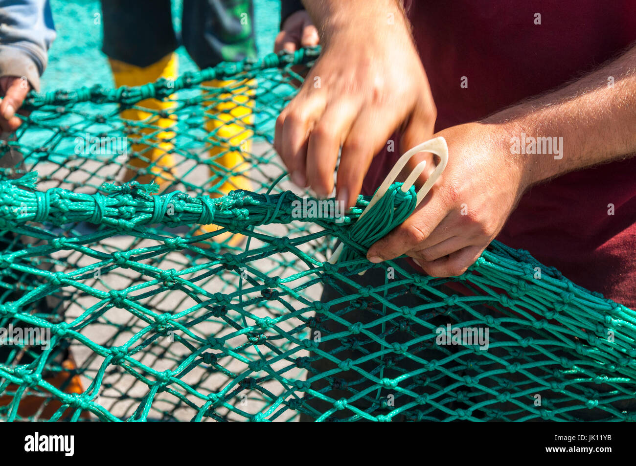 Fishermans Hände reparieren ausbessern Netze in Killybegs Hafen County Donegal, Irland Stockfoto