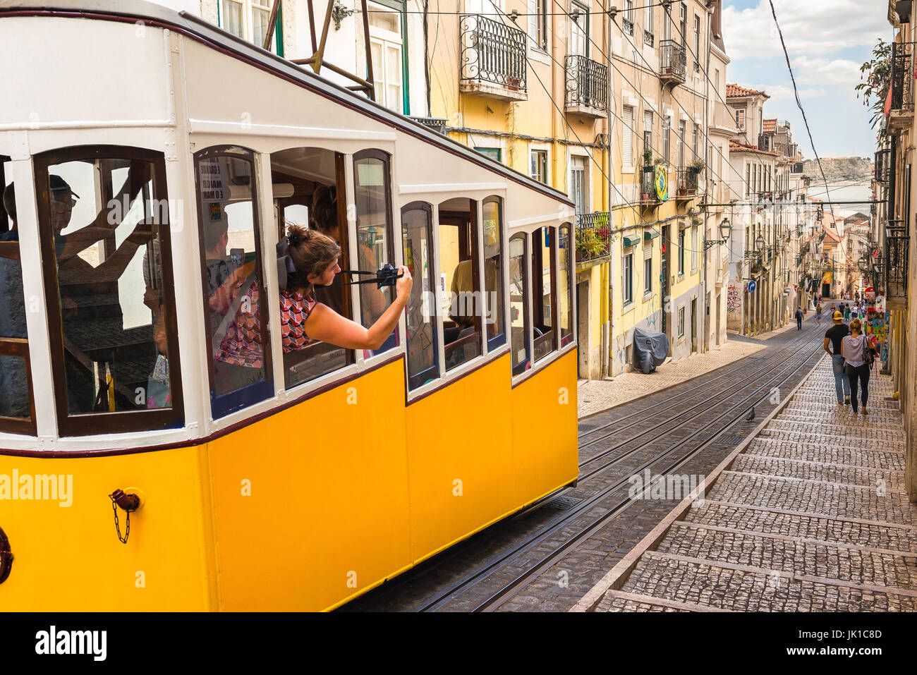 Lissabon Straßenbahn Touristen, lehnt sich ein Tourist aus einer Straßenbahn, der Abstieg von der Elevador da Bica in der Bairro Alto Gegend von Lissabon, Portugal zu fotografieren. Stockfoto