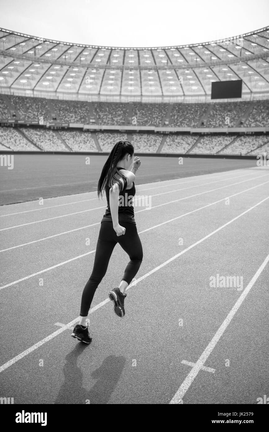 Rückansicht des jungen Fitness Frau Sportswear sprinten auf Laufstrecke Stadion, schwarz / weiß Foto Stockfoto