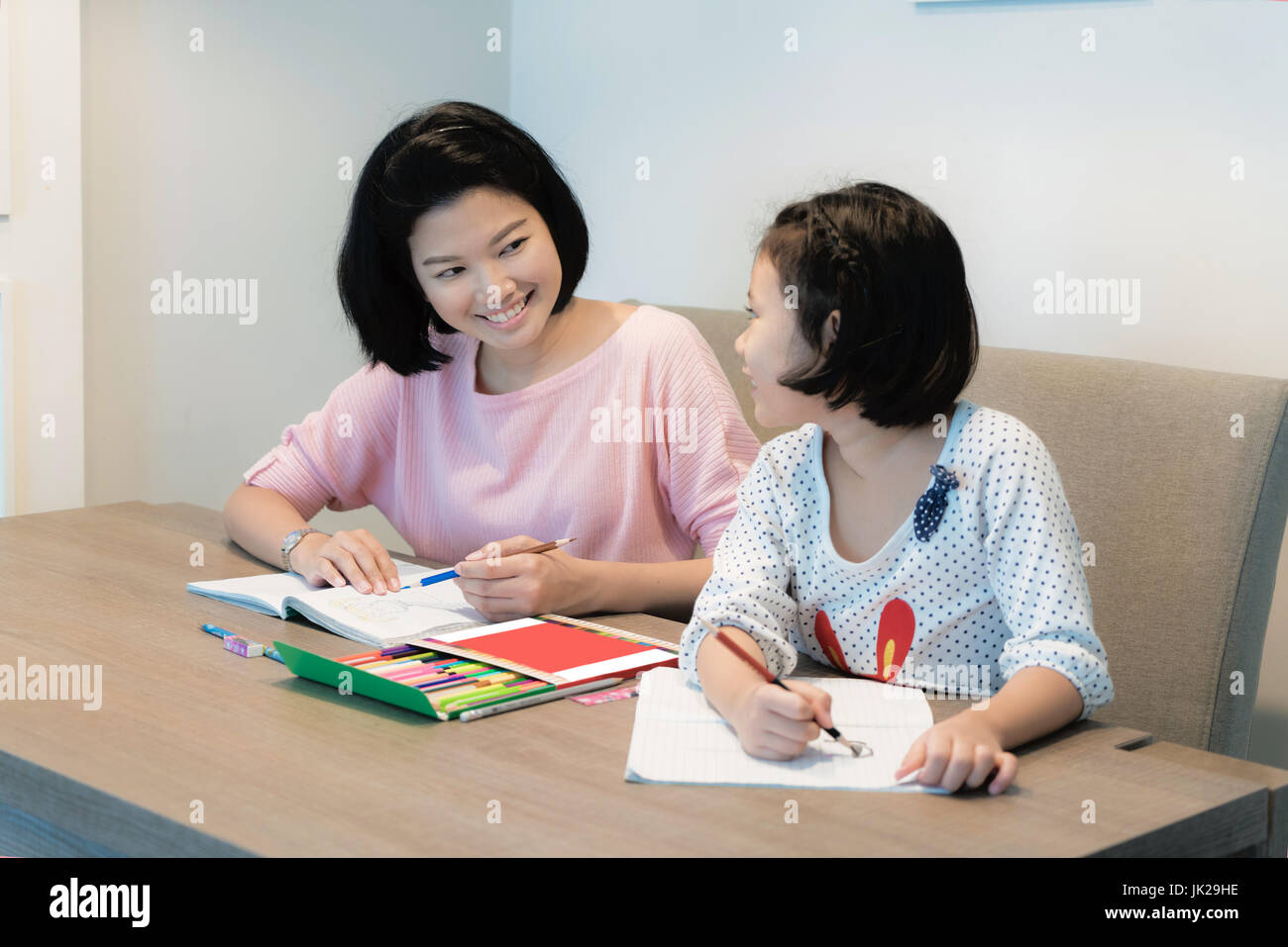 Asiatische Familienglück. Asiatische Mutter und Tochter zusammen zeichnen und malen in Buch. Erwachsene Frau hilft das Kind Mädchen zu Hause Hausaufgaben zu machen. Stockfoto