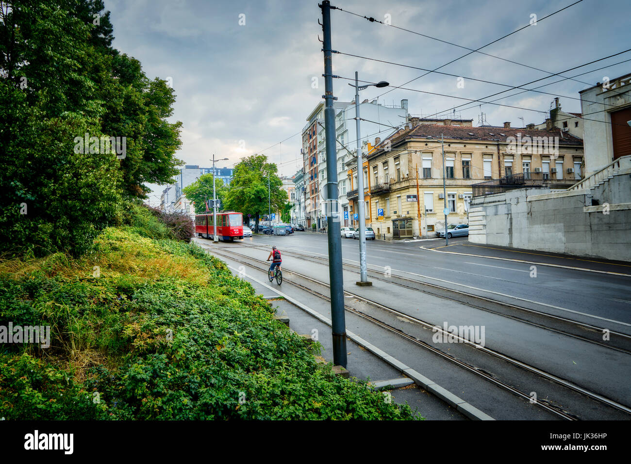 Ein Mann Radfahren als Straßenbahn vorbei in Belgrad, Serbien. Stockfoto