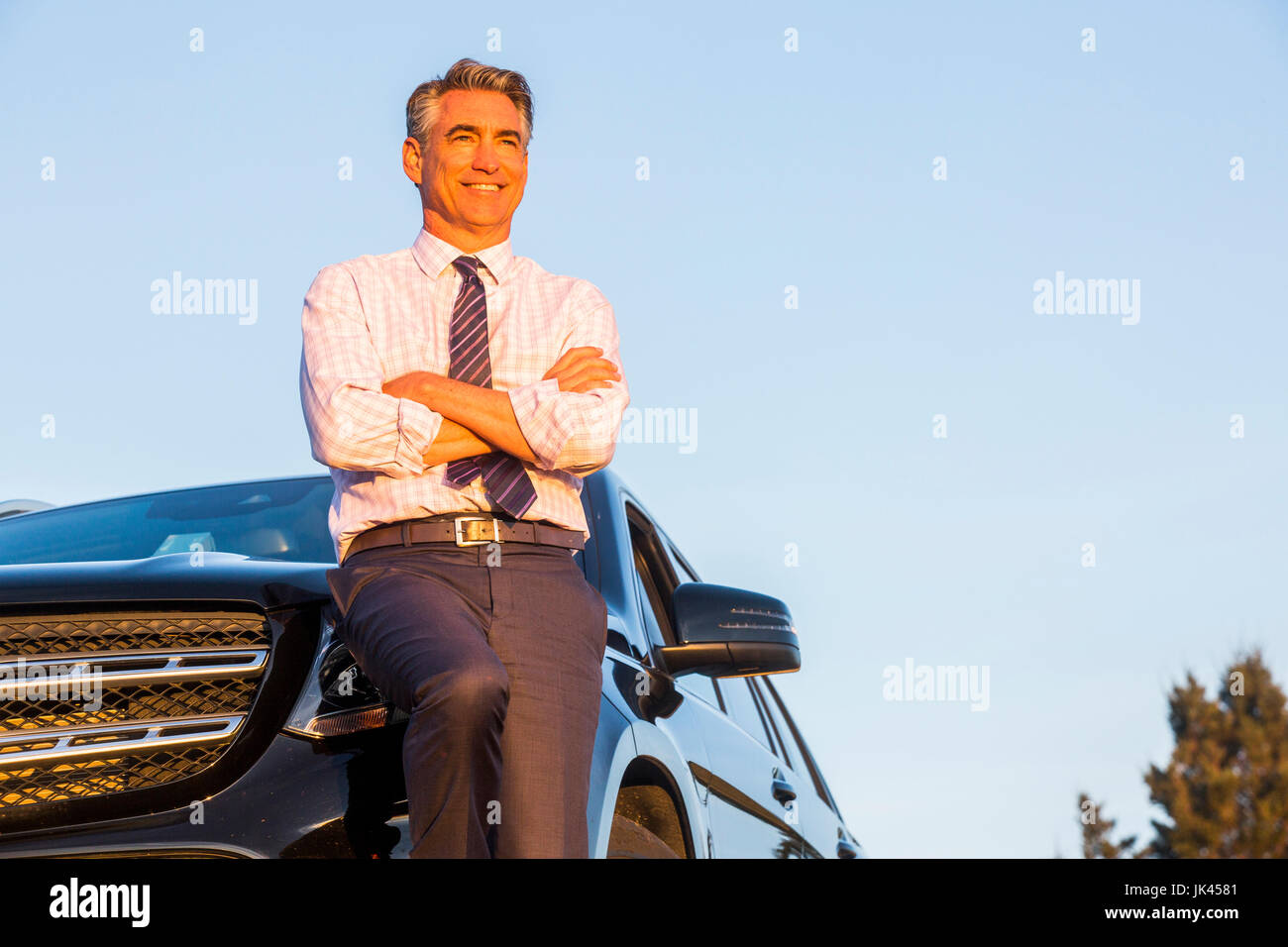 Lächelnd kaukasischen Geschäftsmann stützte sich auf Auto Stockfoto
